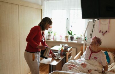 Cuidadora sirve té a una señora mayor en su habitación