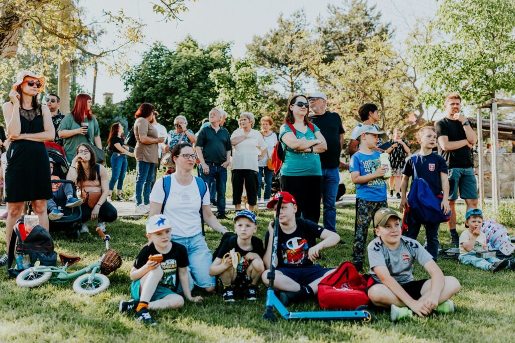 Familias sentadas en el pasto durante un evento comunitario al aire libre en un parque