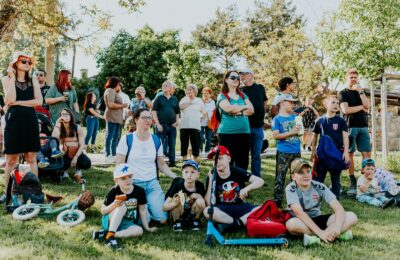 Familias sentadas en el pasto durante un evento comunitario al aire libre en un parque