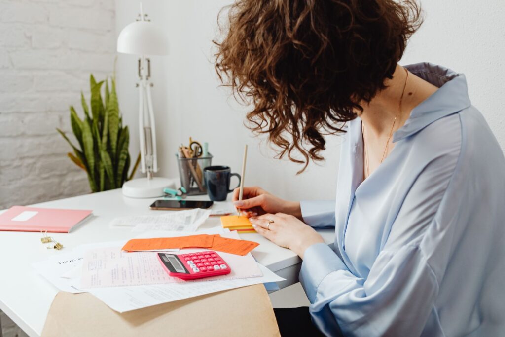 Mujer hace cuentas con calculadora y recibos en su escritorio