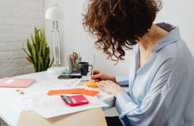 Mujer hace cuentas con calculadora y recibos en su escritorio