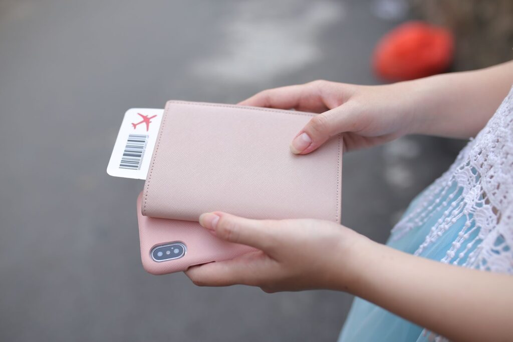 Manos sostienen un pasaporte con funda rosa y un pase de abordar