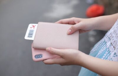 Manos sostienen un pasaporte con funda rosa y un pase de abordar